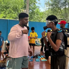 An instructor provides one-on-one guidance on how to use the scuba regulator before a participant enters the pool.