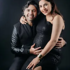 A glamorous studio portrait of an expecting couple. The mom-to-be shines in a black sequin dress while her partner holds her close, creating a timeless and elegant memory.