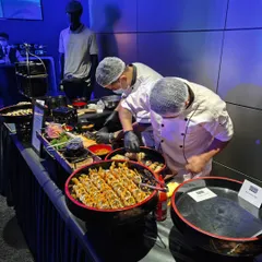 Our sushi chefs meticulously preparing rolls at a live sushi counter. Offering freshly made sushi adds a touch of sophistication and provides a healthy, delicious option for guests at corporate and social events.