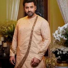 A classic portrait of the groom in an elegant, soft-colored kurta. The simple, clean background keeps the focus entirely on him.