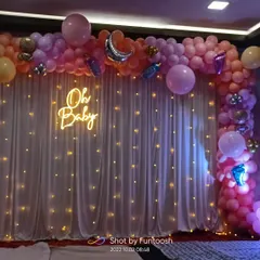 The beautiful balloon arch for the baby shower, featuring a mix of pastel pink, orange, and purple balloons with silver moon and bottle-shaped foil accents.