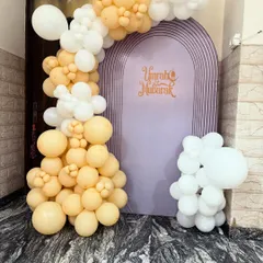 I also provide decorations for religious occasions. This 'Umrah Mubarak' setup features an elegant purple arch backdrop with custom lettering, framed by a beautiful arrangement of pastel yellow and white balloons.