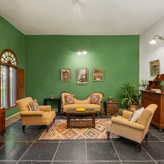 The living area of the Arundati suite, featuring a vibrant green wall, antique furniture, and traditional Indian art, perfect for relaxed family portraits.