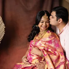 A sweet kiss and a happy smile. This intimate moment captures the joy of the parents-to-be during their traditional saree maternity shoot. The rich fabrics and colors make the photo feel so warm.