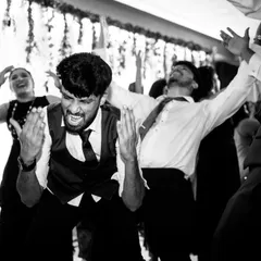 The raw energy of the Sangeet dance floor captured in a dynamic black and white photo, showing guests completely lost in the music.