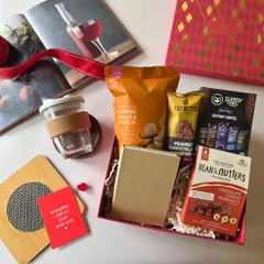 A beautiful flat-lay of a Valentine's Day hamper, filled with coffee, snacks, and a reusable cup. It's the perfect gift for your boyfriend or girlfriend.