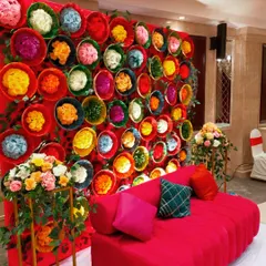 A unique and colorful backdrop for a Mehendi ceremony, created using dozens of baskets filled with dyed flowers. This creative and vibrant wall provided a fantastic photo opportunity for guests.