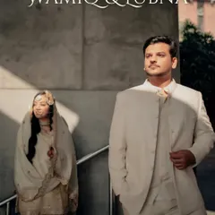 A regal portrait of Wamiq and Lubna, their coordinated ivory outfits exuding timeless elegance. The groom's confident stance complements the bride's graceful presence.