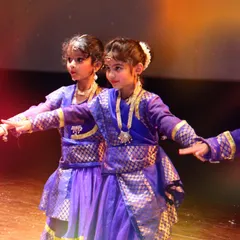 A close-up of two young performers in beautiful blue and gold traditional costumes for their Kathak piece. The detailed attire and focused expressions show their dedication to the art form.