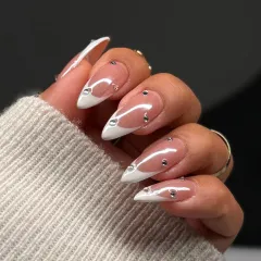 A side view of the embellished French manicure, showing the elegant almond shape and the precise placement of the gems.