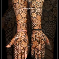 This full-coverage bridal mehendi design extends up to the elbows, perfect for the bride who wants a rich and traditional look. It features bold, shaded roses and other floral motifs, combined with intricate jaali net patterns and classic details on the palms.