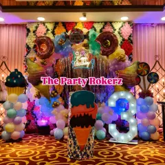 Welcome to Candyland! I love creating these sweet themes with giant donut and ice cream props, a colorful balloon arch over a shimmer wall, and a large light-up number for the birthday child's age. It's a vibrant and fun setup for any party.