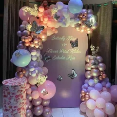 A beautiful butterfly-themed celebration with a custom arched backdrop and a lush balloon garland in shades of pink and purple.