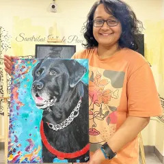 A student at my Pune studio shows off her completed pet portrait, a detailed and colorful acrylic painting of her beloved black Labrador.