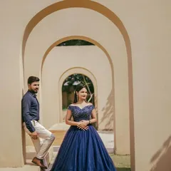 A couple posing in a grand archway, featuring a sparkling navy blue ball gown. This dress is perfect for an elegant pre-wedding theme that requires a touch of royalty.