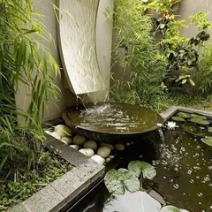 Landscaping is an art. This zen garden corner was designed around a sculptural, curved waterfall that creates a gentle sound as it flows into a basin and overflows into a small lily pond. The use of natural stone and bamboo completes the tranquil atmosphere.