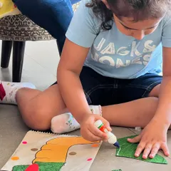 A close-up of a child deeply focused on making her dragon paper bag puppet. These moments of quiet concentration and creativity are just as magical as the loud, giggly ones.