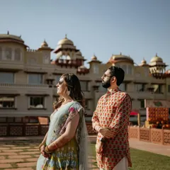 A stylish portrait of the couple against the magnificent facade of a heritage palace. Their modern-meets-traditional outfits and confident poses create a powerful and fashionable pre-wedding image.