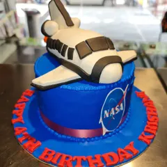 An out-of-this-world 3D sculpted cake for a future astronaut. This NASA space shuttle cake is crafted with smooth blue fondant and a detailed, edible shuttle, showcasing my skill in creating unique, three-dimensional designs.