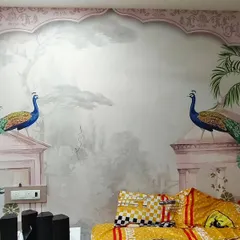 A beautiful bedroom mural featuring peacocks perched on pink Rajasthani architectural elements. This installation brings a grand, palatial feel to the room.