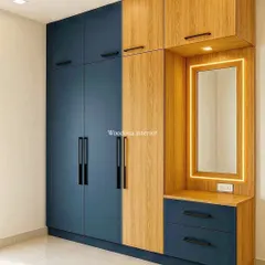 A floor-to-ceiling wardrobe doesn't have to be boring. I designed this two-tone unit in blue and wood laminate, integrating a dressing table with profile lighting. This design provides ample storage while adding a modern, stylish look to the bedroom.