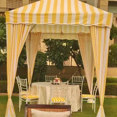 A close-up of a private dining cabana from the brunch setup. The yellow and white stripes, combined with elegant seating, create a perfect spot for an intimate meal.