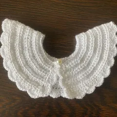 This crisp white detachable collar adds a timeless, elegant look to any outfit. The intricate stitching and scalloped border are details that showcase its handmade quality.