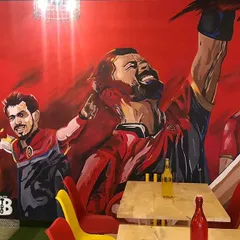 The finished RCB mural in its full glory at the Ee Sala Cup Namde Cafe. The bright red background and dynamic poses make the whole space feel energetic.