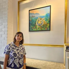 Artist Mrinalini showcases her vibrant painting of a tiger in a lush, natural setting, a piece from our "Roar of Art" exhibition.