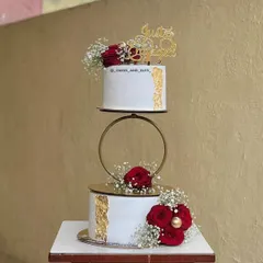 We love being part of new beginnings. This two-tier engagement cake features a delicate gold hoop separator and is adorned with fresh red roses and baby's breath. You can learn how to properly prep and place fresh florals on cakes for a food-safe and beautiful finish.