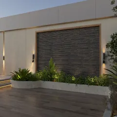 This detail of the terrace shows the built-in planters and a feature wall with wooden slats. The strategic use of up-lighting creates a sophisticated ambiance in the evening, highlighting the textures of the plants and materials.