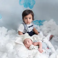 A big brother watches over his sleeping sibling from a bed of clouds. This portrait captures the beginning of their journey as brothers and best friends.