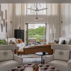 The formal living area features a dramatic double-height ceiling and floor-to-ceiling moulded walls. We used classic English roll-arm couches and a bold mustard chaise to define the space and create a warm, lived-in, and collected vibe.