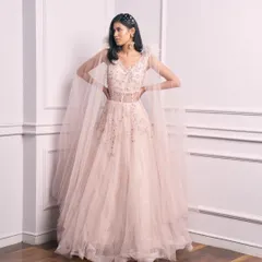 Live out your fairy tale dreams in this pale pink Indo-Western princess gown. The delicate embellishments and cape sleeves make it a magical choice for a reception or prom.