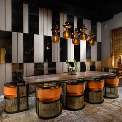 This dining space is a study in contrasts. I combined leather, mirror, and metal strips for the wall panelling to create a bold, graphic effect. The vibrant orange velvet chairs and stone-top table complete this energetic and luxurious setting.