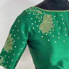Serving looks in this stunning green blouse. The delicate lotus flower, hand-embroidered with golden thread, adds a touch of luxury and confidence to this beautiful piece.