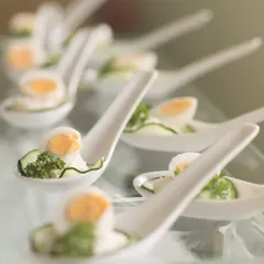 Elegance in a single bite. These spoon appetizers feature perfectly cooked quail eggs with a light dressing and fresh herbs, showcasing a simple yet sophisticated option for cocktail hours and receptions.