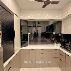 A U-shaped modular kitchen with a dual-tone finish. The design includes handleless drawers, a rolling shutter for appliances, and glass-front upper cabinets.