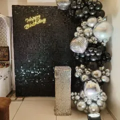 A chic and modern party corner with a black sequin wall. The balloon arch with black, silver, and disco ball accents, along with a neon 'Happy Birthday' sign, is perfect for a stylish office celebration.