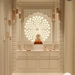 This elegant mandir design features a backlit floral mandala pattern behind the main idol. The space is beautifully illuminated with hanging pendant lights and features clean white cabinetry for storage, blending traditional motifs with contemporary design.