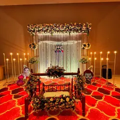 The same beautiful cradle ceremony setup, showcasing the vibrant red patterned carpet that adds richness to the decor.