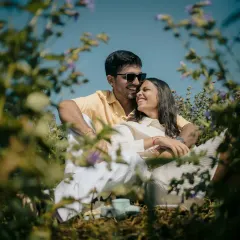 A creative shot through the foliage, making it feel like a secret, stolen moment. The couple's relaxed pose and sunglasses add a cool, casual vibe to this romantic scene.