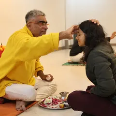 A student receives a blessing during her initiation. This act symbolizes the transmission of energy and wisdom from the guru to the shishya, igniting the spiritual potential within.