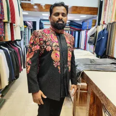 A client showcasing a stunning black Indo-Western jacket with vibrant, multi-colored floral embroidery. This is a bold and artistic piece for any celebration.