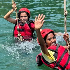 Two participants enjoy a rope swing activity in the water, a fun and thrilling part of our Dandeli camp.