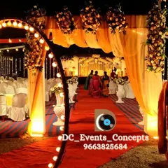 A grand entrance for an outdoor event, with a red carpet pathway, an illuminated circular arch, and warm, draped fabrics creating a celebratory walkway.