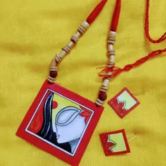 Inspired by the divine feminine, this 'Maa' necklace set is hand-painted on a fabric canvas. The design captures the serene yet powerful essence of Durga, set against a vibrant red and yellow background. It's a piece of spiritual art you can wear, paired with delicate matching earrings.