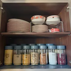 We maximize cabinet space by using shelf risers for plates and dedicating the lower shelf to neatly labeled jars of dals and grains. This creates two distinct, easy-to-access zones in one cabinet.