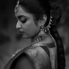 A classic black and white profile of a South Indian bride. The focus on her traditional jewelry, braided hair, and elegant posture highlights the timeless beauty of her bridal look.