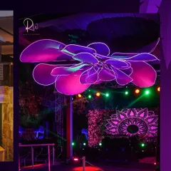 A massive, custom-made neon floral installation was suspended over the dance floor, bathing the space in a vibrant purple and pink glow and creating a high-energy focal point.